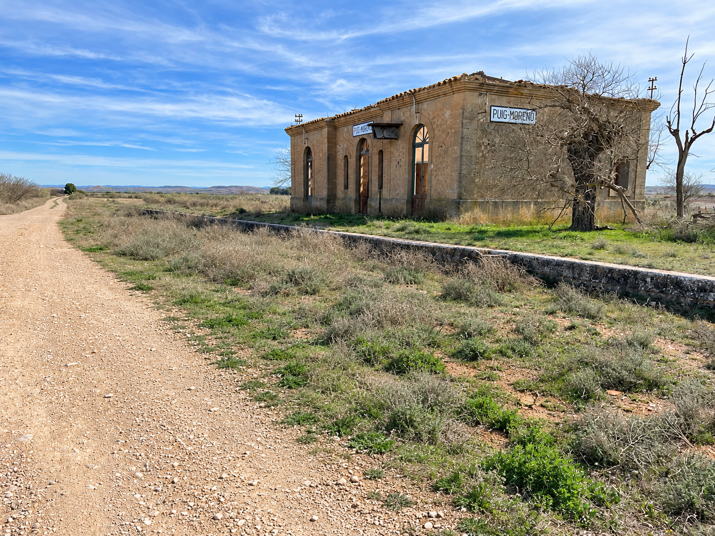 Antigua estación de Puig-Moreno junto a un camino rural, con el nombre visible en la fachada